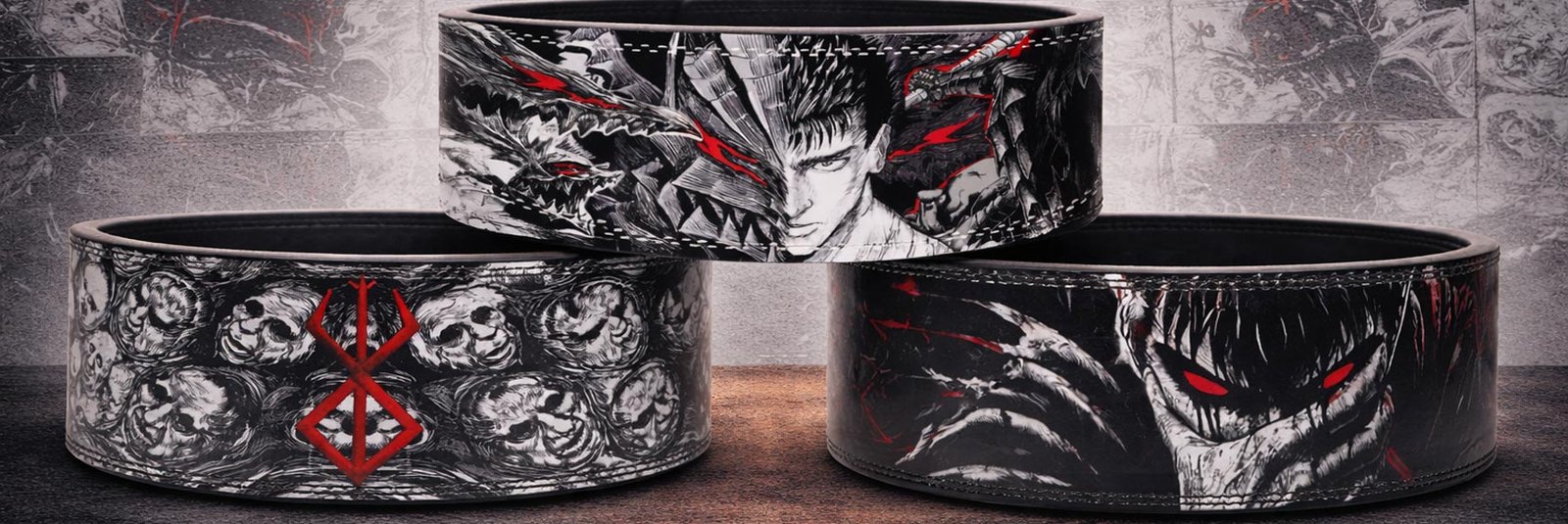 Three custom weightlifting belts featuring Berserk anime designs, including a split portrait of Guts alongside his Berserker armor, a belt covered in grey skulls centered around a red Brand of Sacrifice, and a dark belt highlighting the glowing red eyes of the Berserker armor.