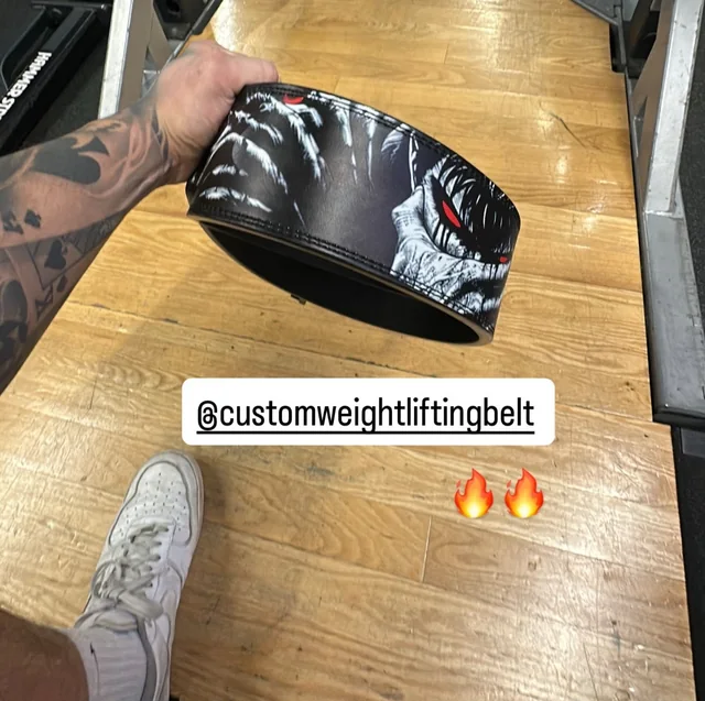 Customer showing a black-and-white Berserk weightlifting belt with red eyes in a gym.